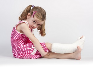 A young girl shows her broken leg in a cast