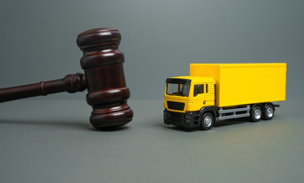 Gavel beside a yellow commercial truck symbolizing trucking company liability in accident and personal injury cases.