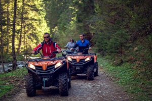 ATV riders on forest trail by river