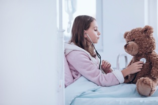 A Young Cancer Patient With a Stethoscope and Teddy Bear While in the Hospital