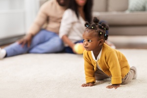 baby crawling on floor with parents in background