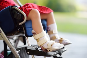child in wheelchair with leg braces