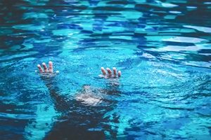 child holding hands up as he sinks in a pool Gray and White Law
