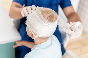 doctor bandaging a child with a head injury