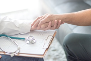 doctor comforting elderly patient nursing home