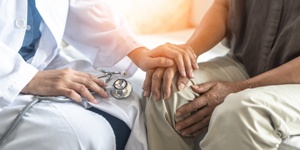 doctor comforting patient by placing his hand on patient's hand