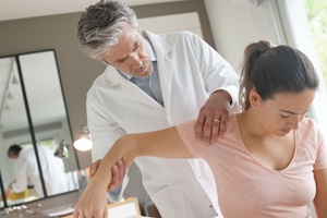 doctor examining woman's shoulder