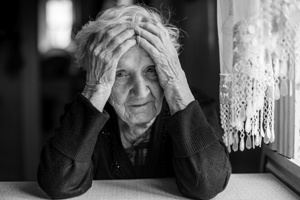 elderly woman holding her head in confusion Gray & White