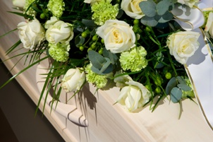 white flowers on top of white casket at funeral