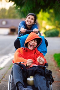 girl pushing brother with cerebral palsy in wheelchair