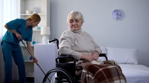 housekeeper cleaning behind nursing home resident in wheelchair