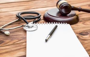 legal pad with judge's gavel and stethoscope