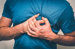 man having heart attack clutching his chest