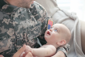 man in army fatigues holding baby