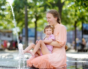 mother holding child with cerebral palsy in outdoor fountain
