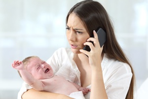 mother holding crying baby calling doctor
