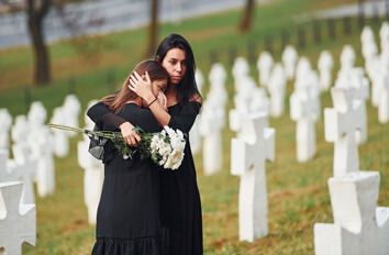 mother and daughter hugging at graveside funeral service