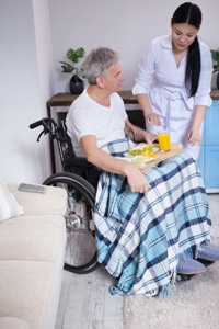 nurse serving breakfast to elderly man in wheelchair