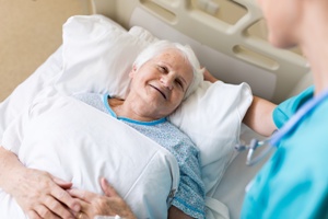 nursing home resident in bed talking to staff member