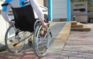 person in wheelchair approaching wheelchair ramp to home