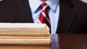 pile of folders in front of man in suit