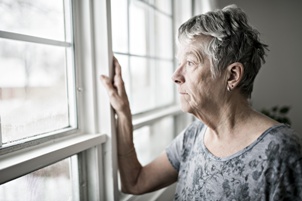 sad elderly woman looking out window