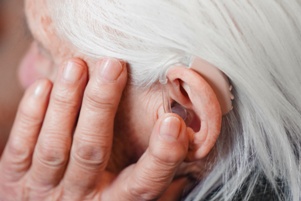 senior adjusting hearing aid in ear