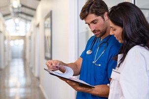 surgeon consulting doctor with clipboard in hospital hallway