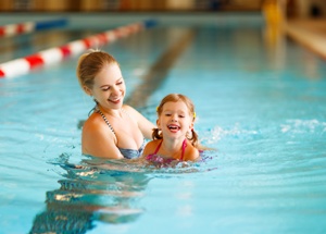 swim teacher in pool with young child