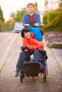 teen girl pushing teen boy with cerebral palsy in wheelchair