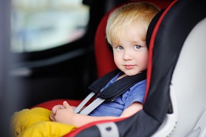 A toddler is secured in his forward-facing car seat