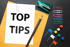Amid a scattering of office supplies is a sign reading TOP TIPS