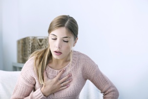 young woman having asthma attack clutching chest